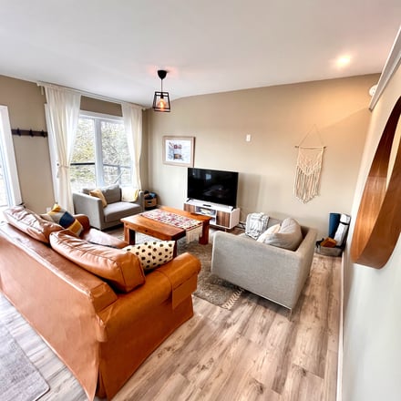 Bright living room with leather sofa, wood coffee table, and large windows